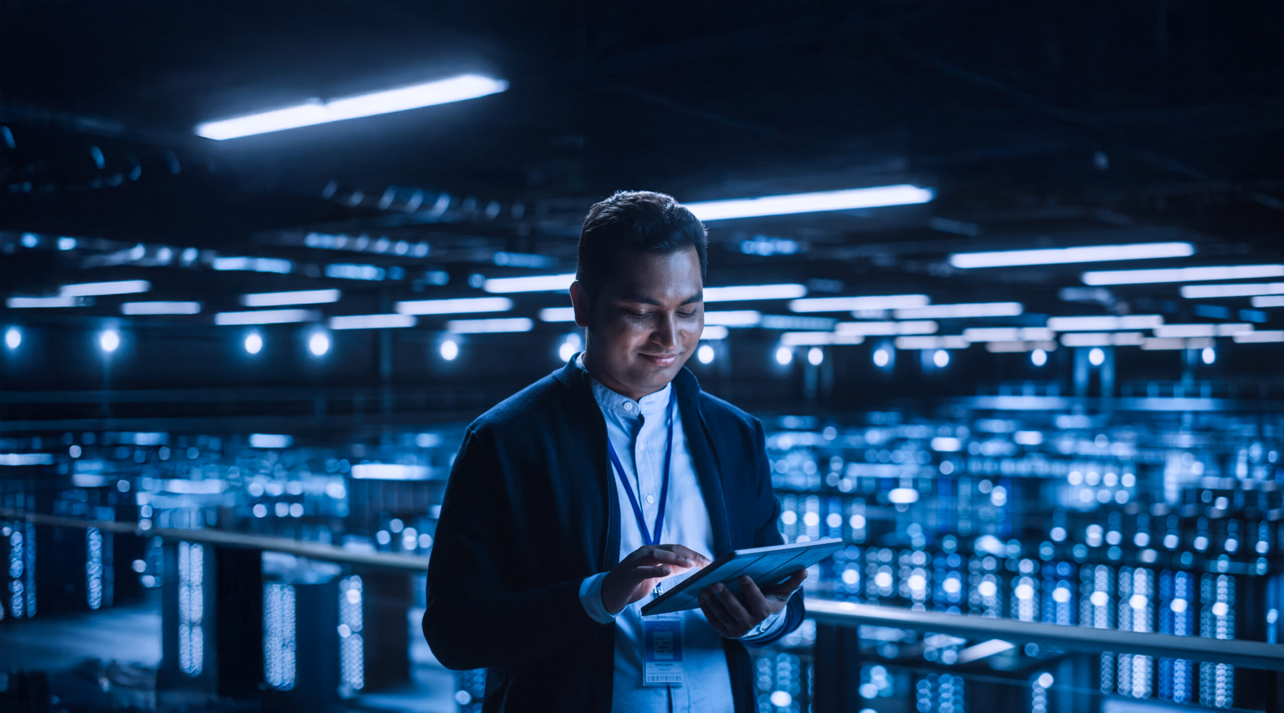 Handsome Smiling It Specialist Using Tablet Computer In Data Cen