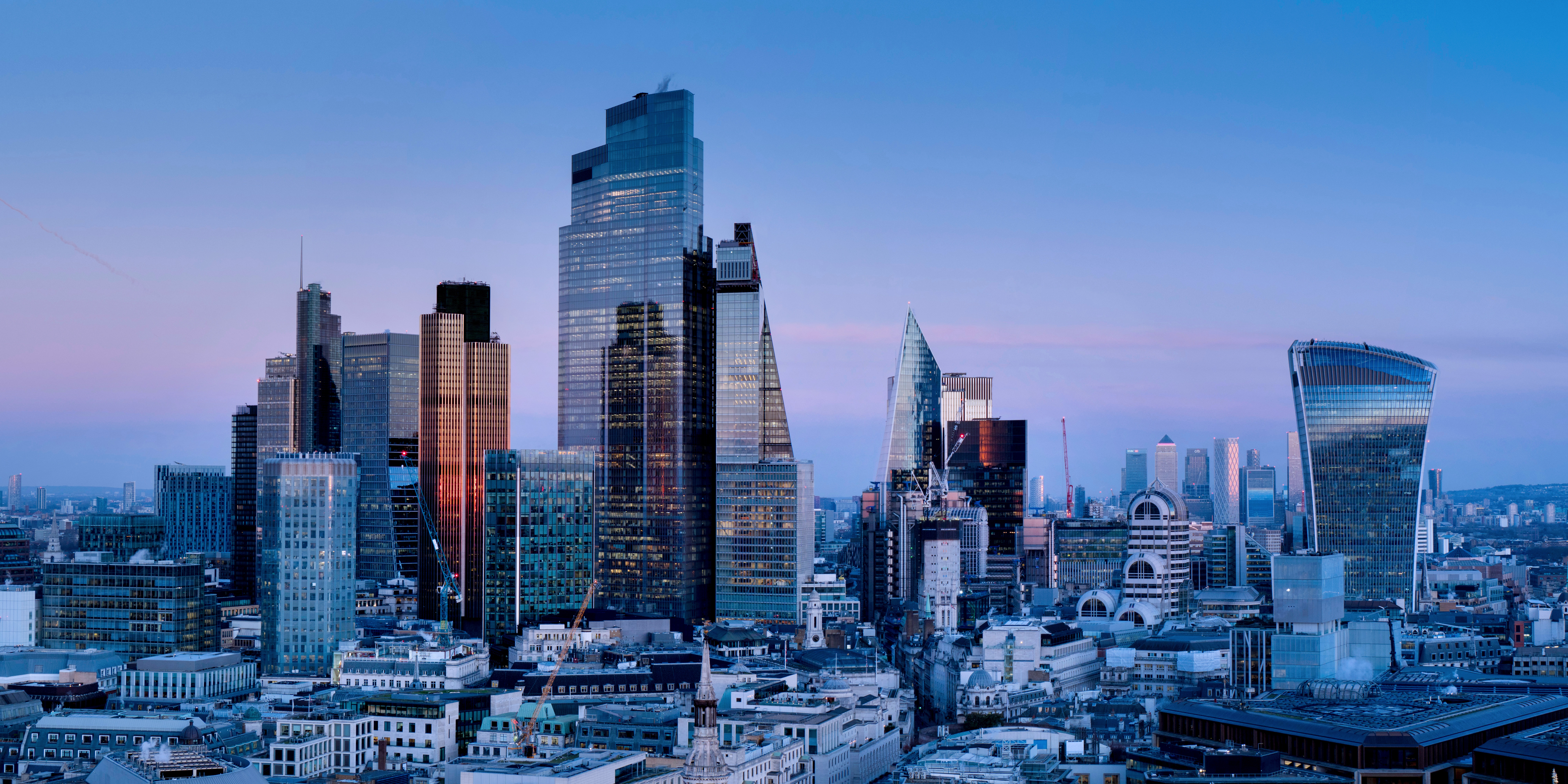 London skyline at dusk featuring prominent skyscrapers such as The Shard, 22 Bishopsgate, and the Walkie Talkie building.